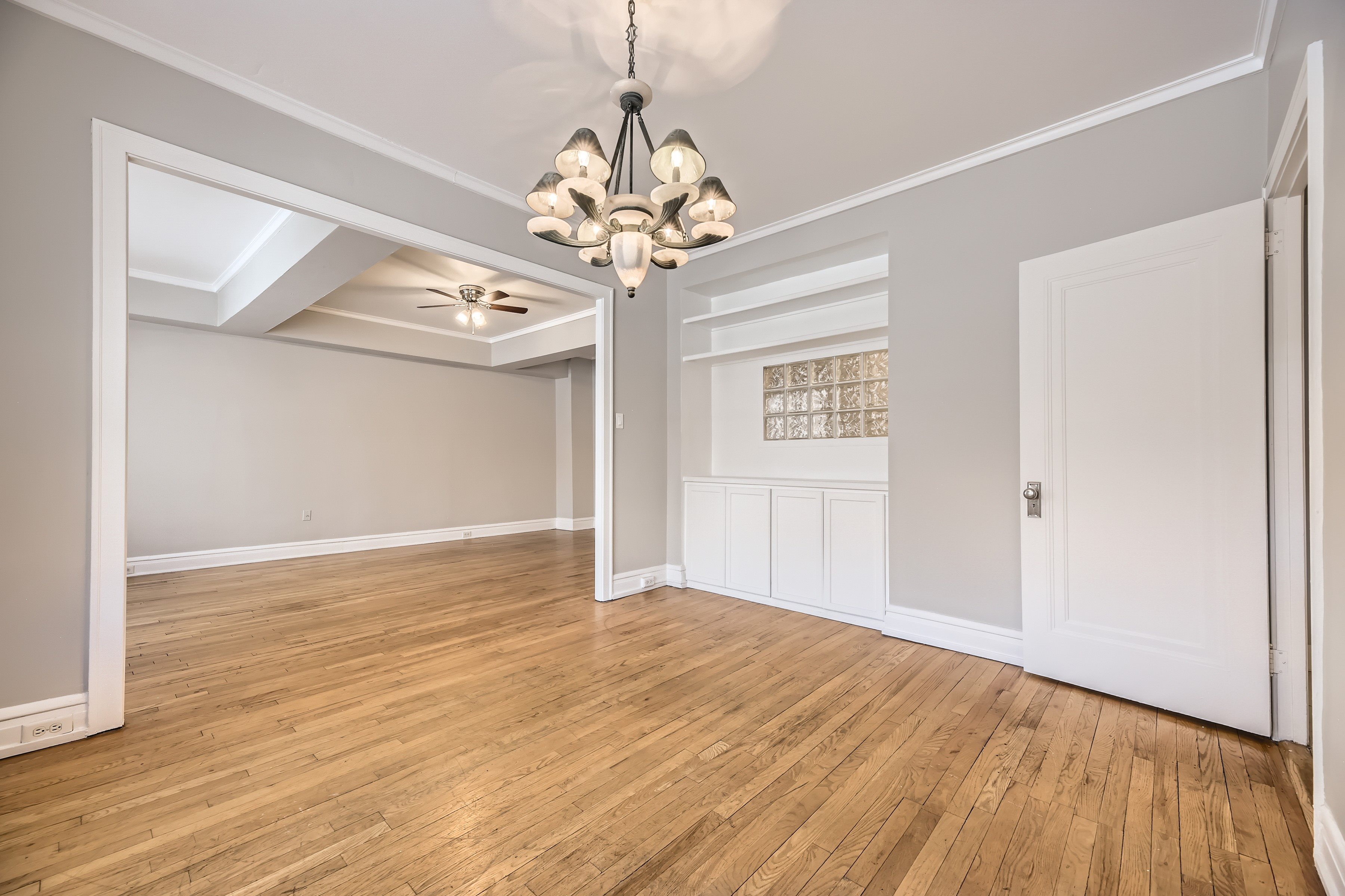 A room with wooden floors and a chandelier hanging from the ceiling.